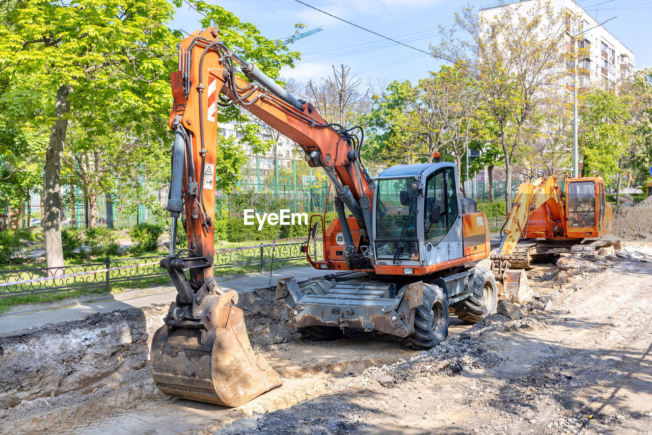 construction industry, transportation, industry, construction machinery, tree, nature, machinery, construction site, plant, mode of transportation, road, day, sunlight, earth mover, construction equipment, road construction, vehicle, asphalt, no people, land vehicle, soil, outdoors, equipment, development, city, sky, dirt, bulldozer