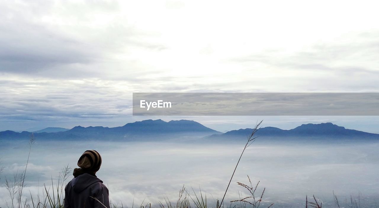 Rear view of man looking at mountain against sky