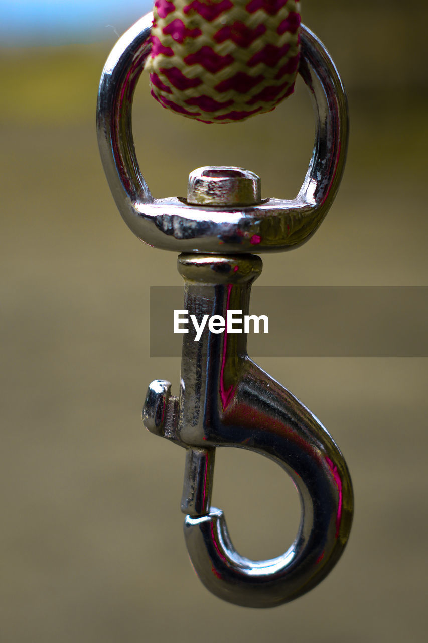 CLOSE-UP OF CAMERA HANGING ON METAL OUTDOORS