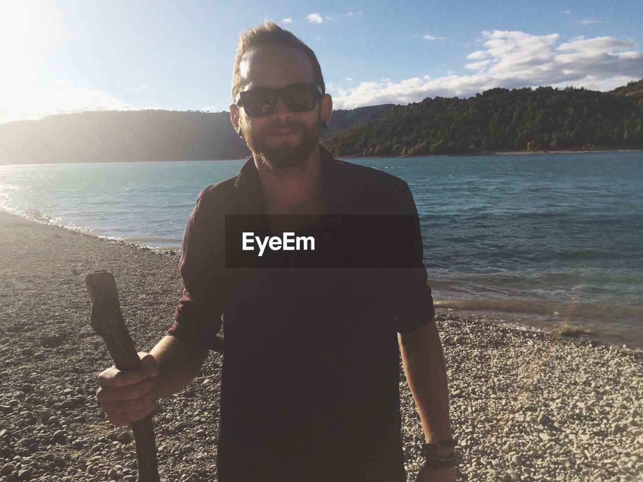 Portrait of bearded young man standing at beach on sunny day