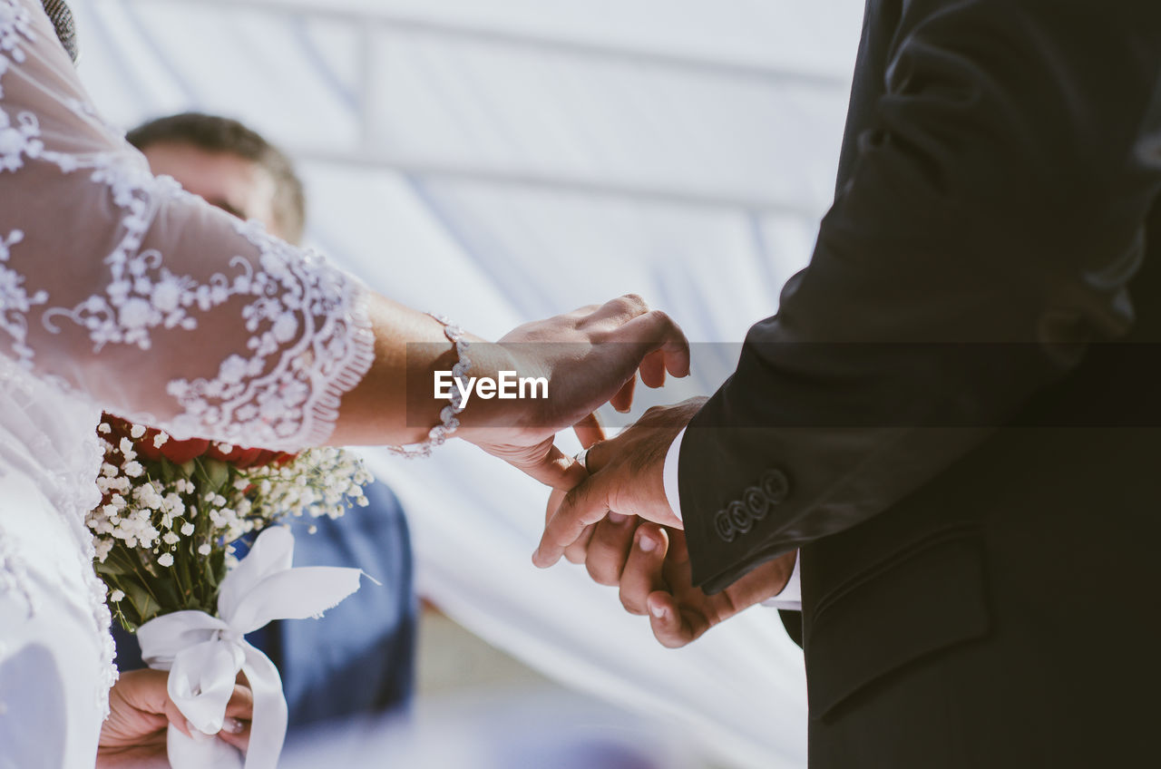 Midsection of bride and groom during wedding