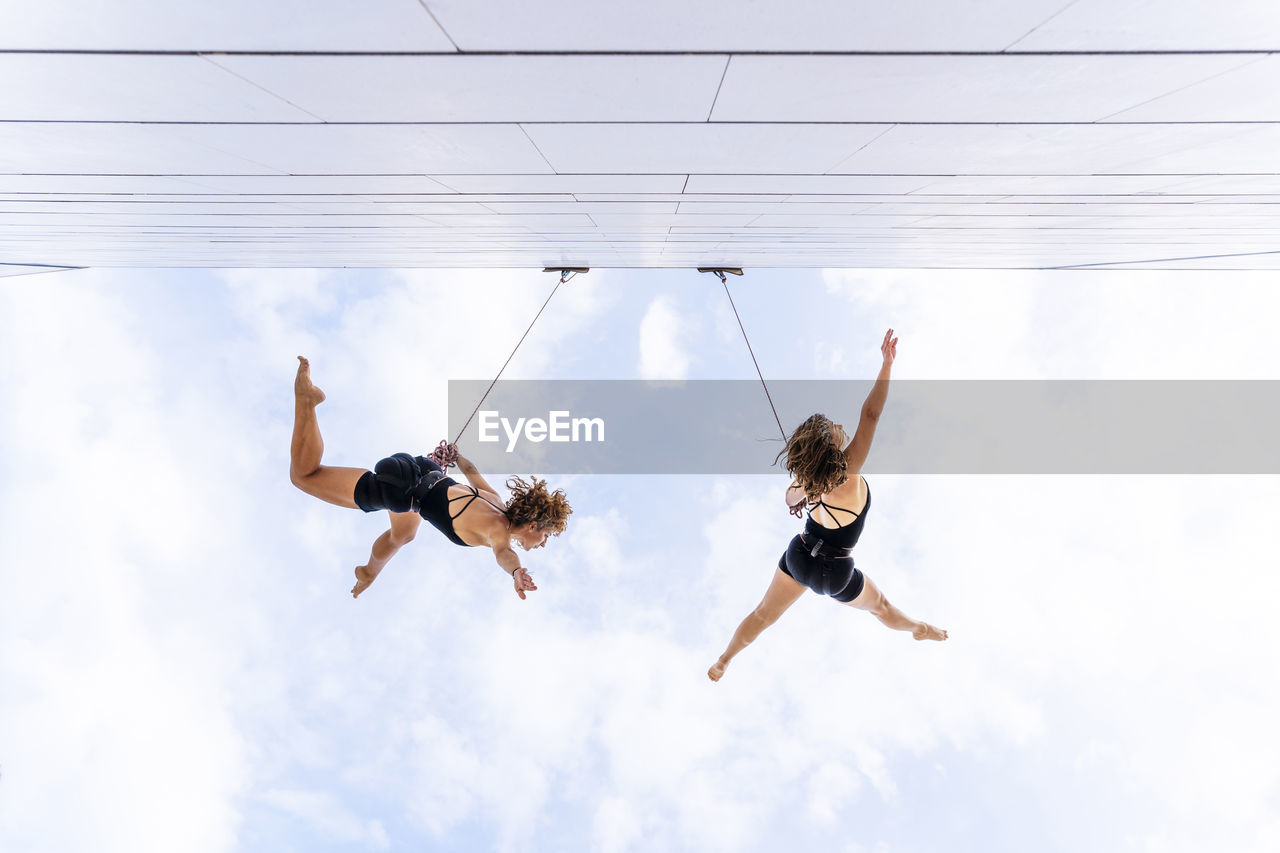 Aerial dancers with hand raised dancing against sky