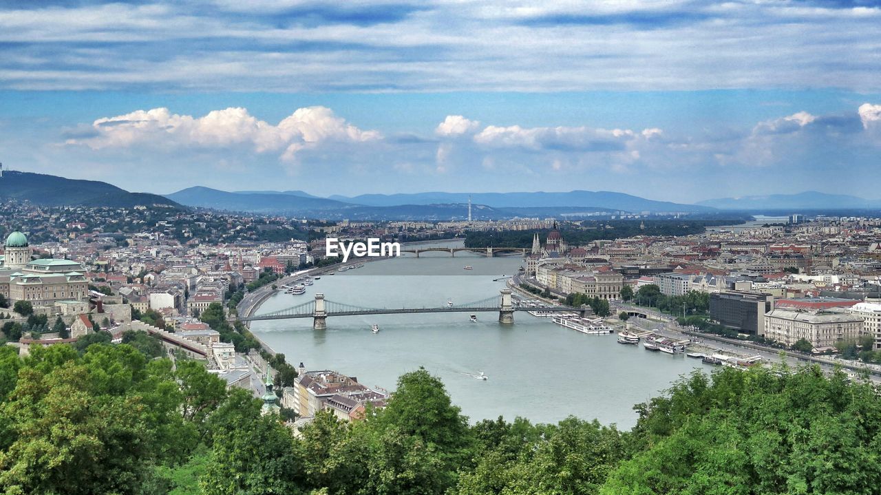 Chain bridge over danube river in city against sky