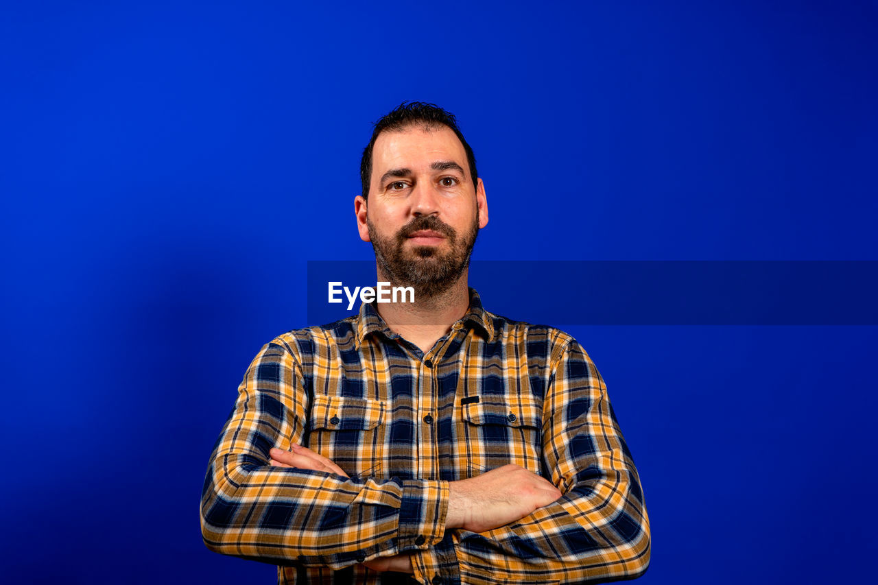 PORTRAIT OF MAN AGAINST BLUE WALL