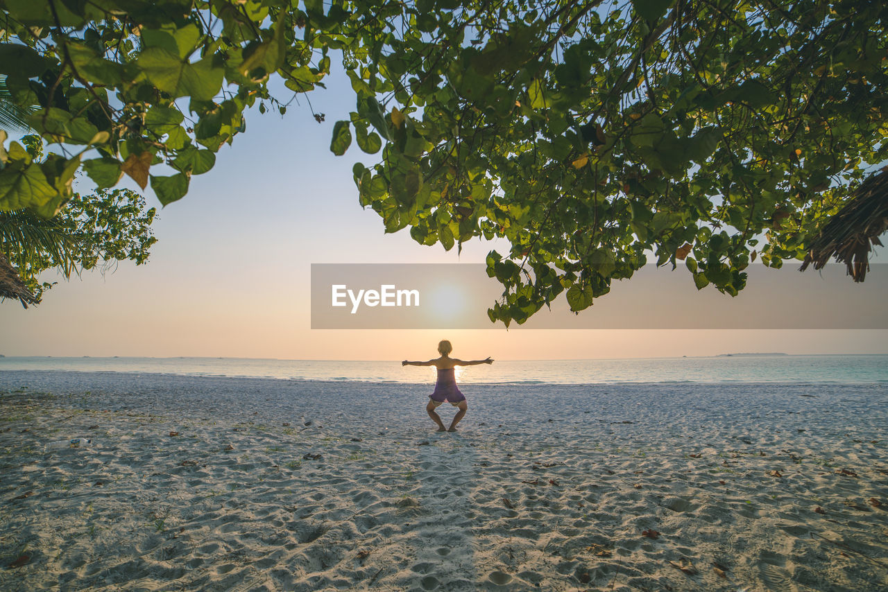 Rear view of woman exercising at beach