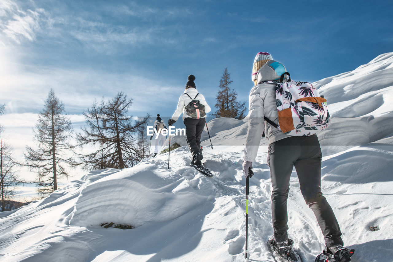 Three women friends on ski trip with snowshoeing on a sunny day
