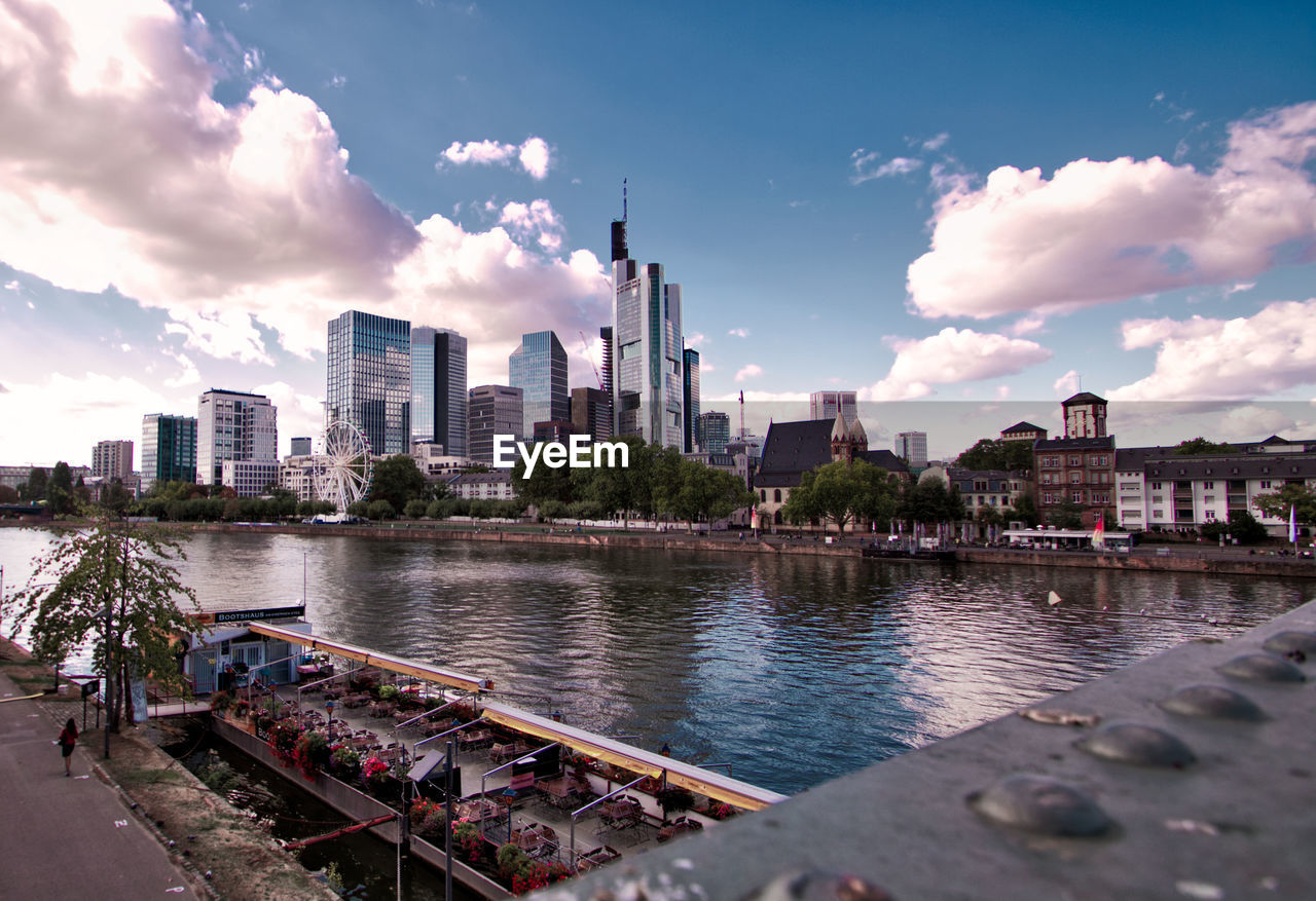 BUILDINGS BY RIVER AGAINST SKY IN CITY