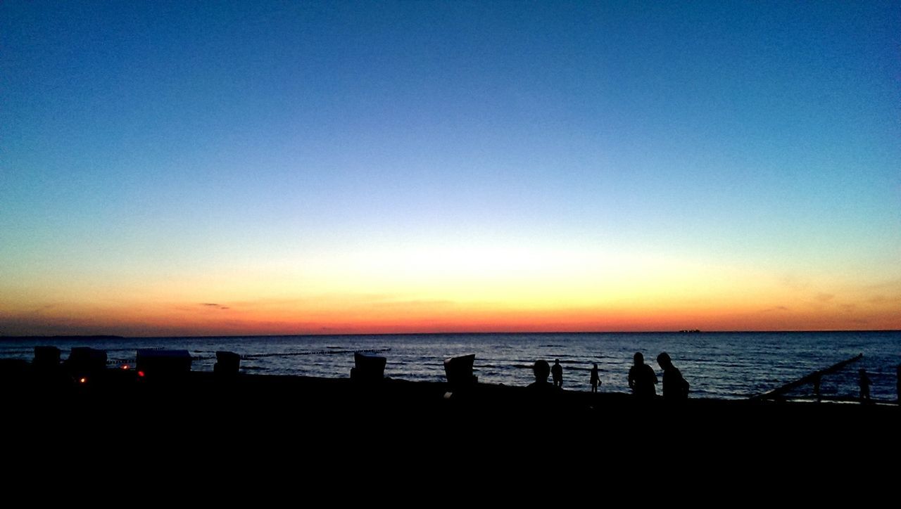 Silhouette tourist on beach against sunset