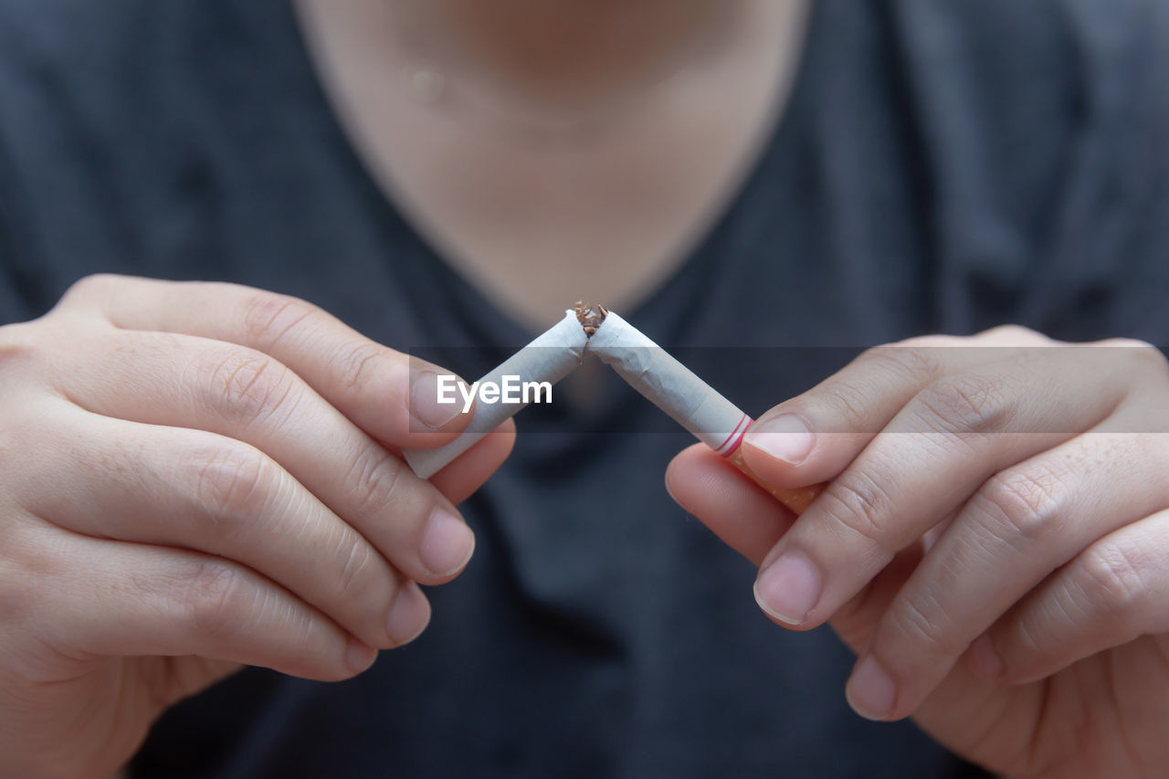 Close-up of man holding broken cigarette