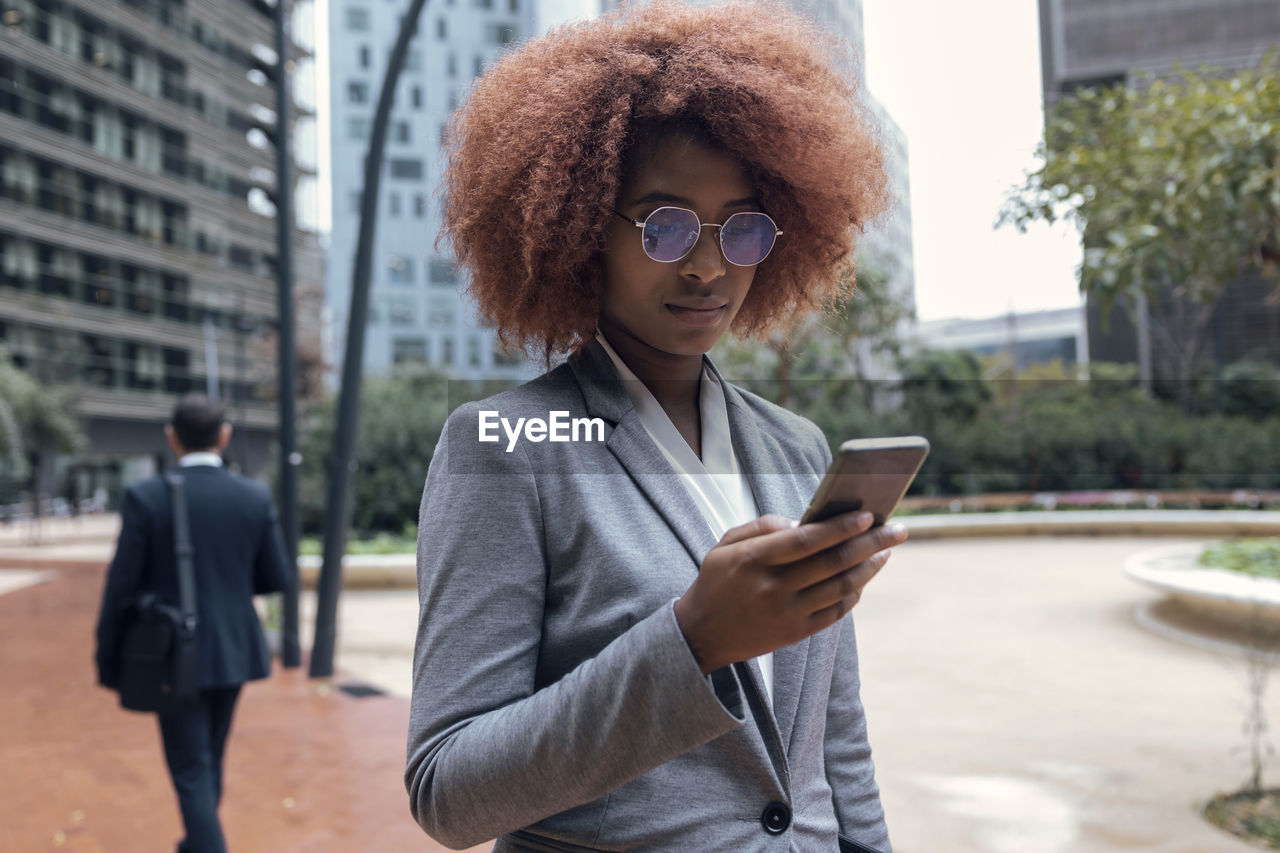 Young businesswoman using smart phone outdoors