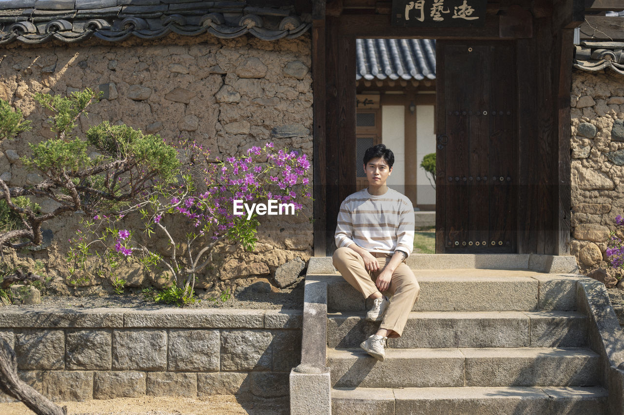 Portrait of man sitting on steps against house