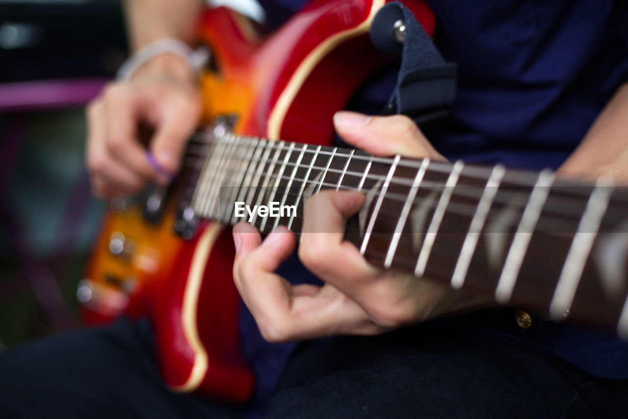 Midsection of man playing guitar