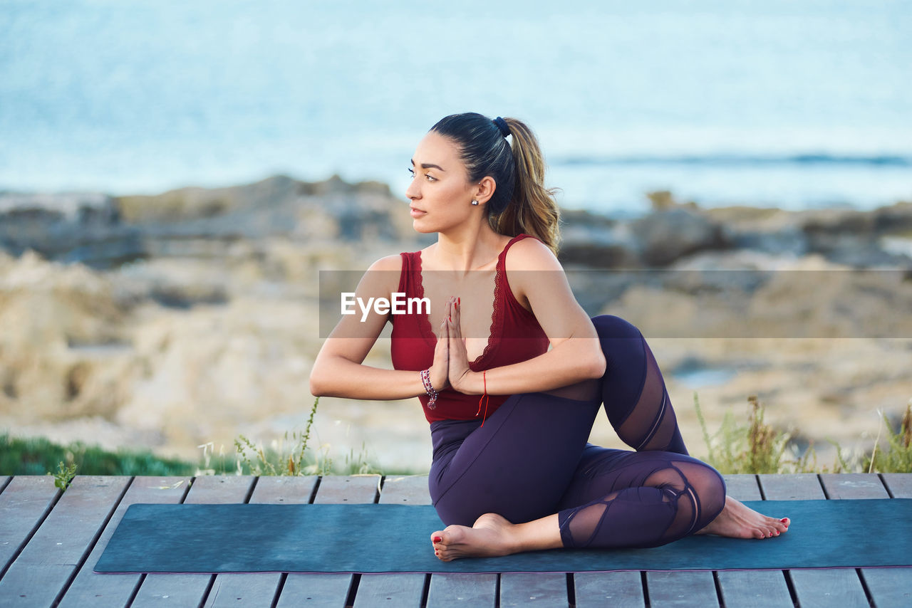 BEAUTIFUL YOUNG WOMAN SITTING ON LAND