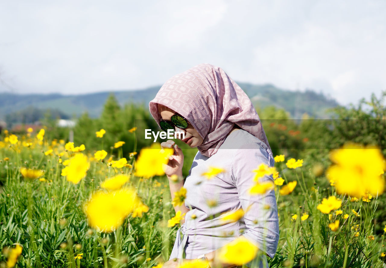 Woman standing in field during sunny day