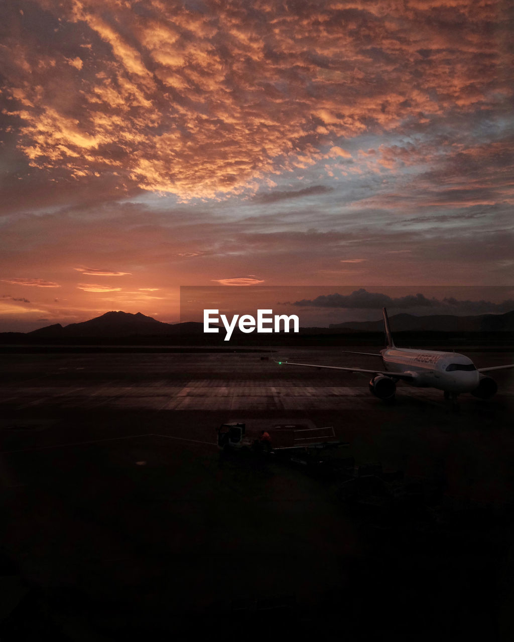 Airplane on runway against sky during sunset
