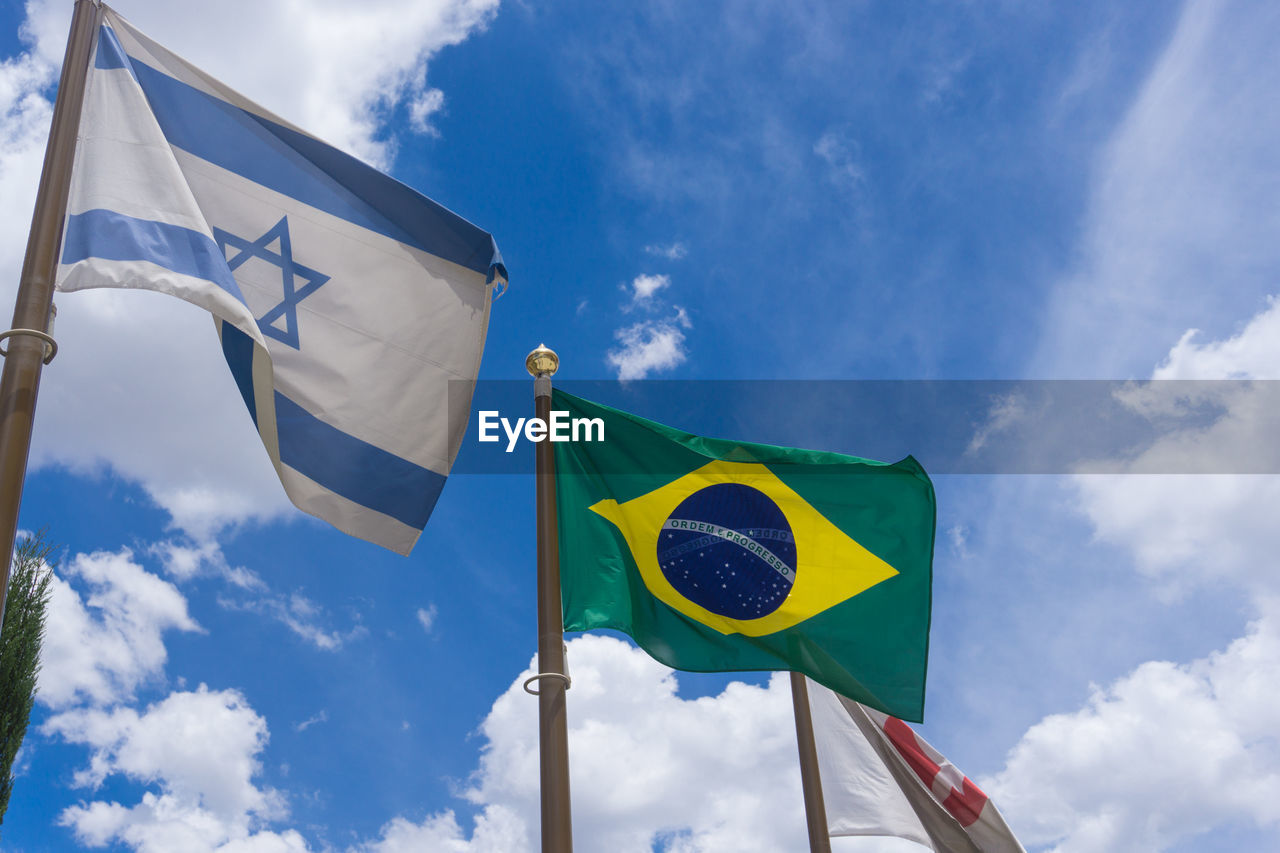 Low angle view of flags waving against cloudy sky