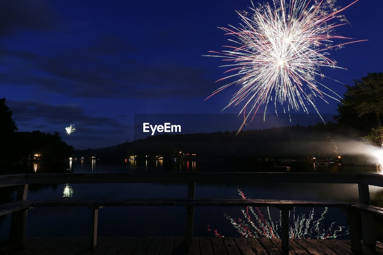 Firework display over river against sky at night