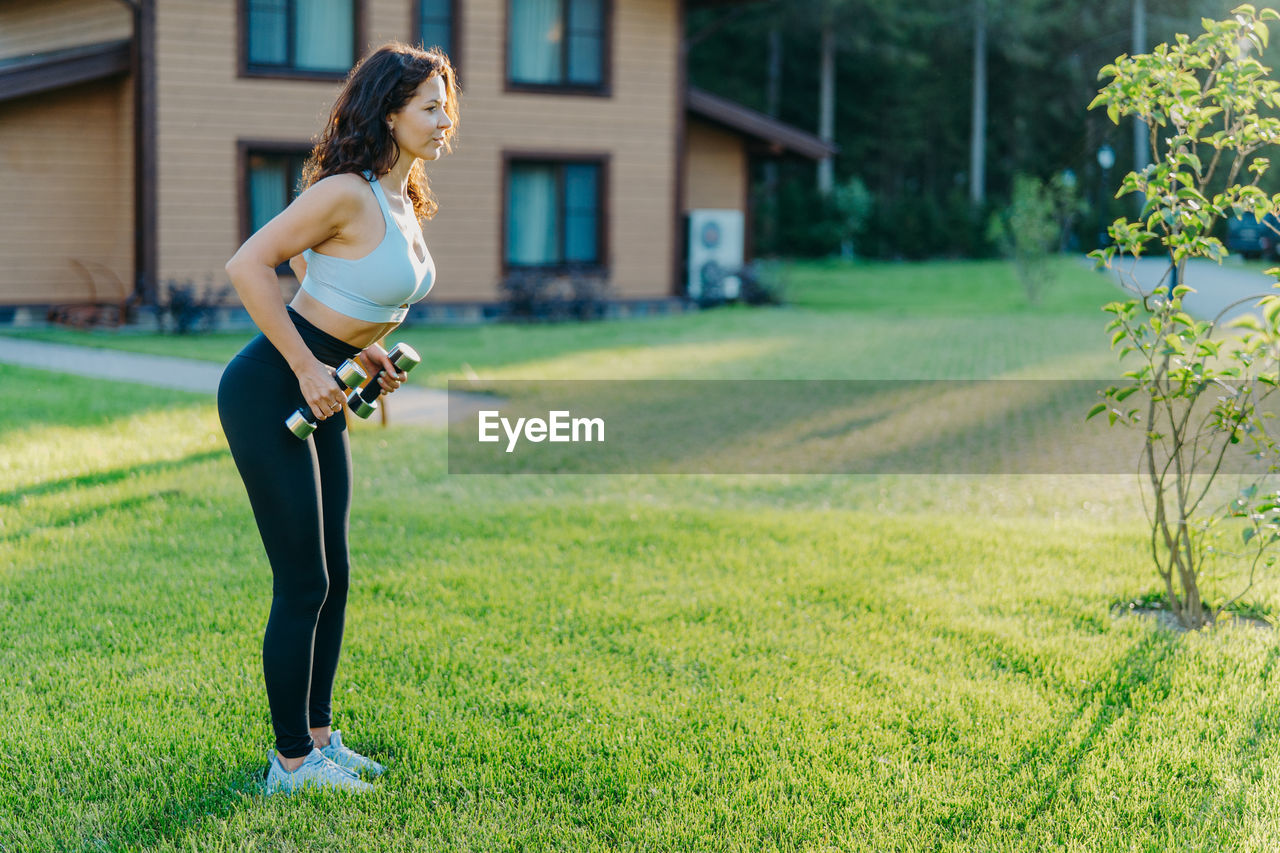 Full length of woman exercising at yard