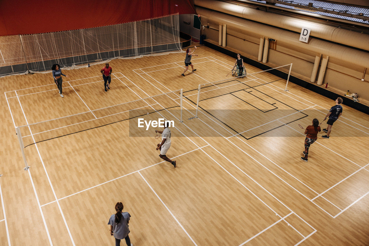 High angle view of male and female athletes playing badminton at sports court