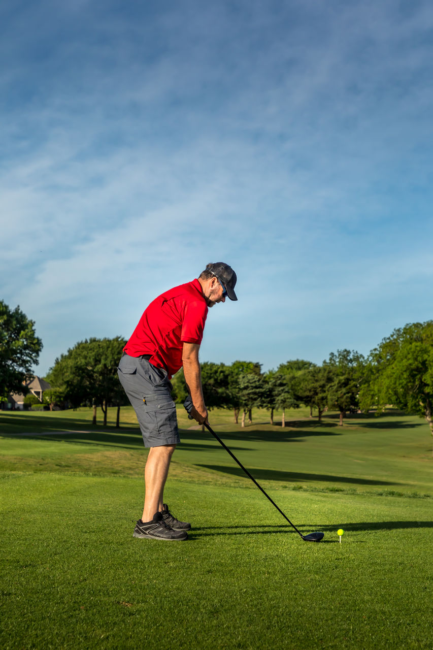 Man teeing off in the tee box, playing golf