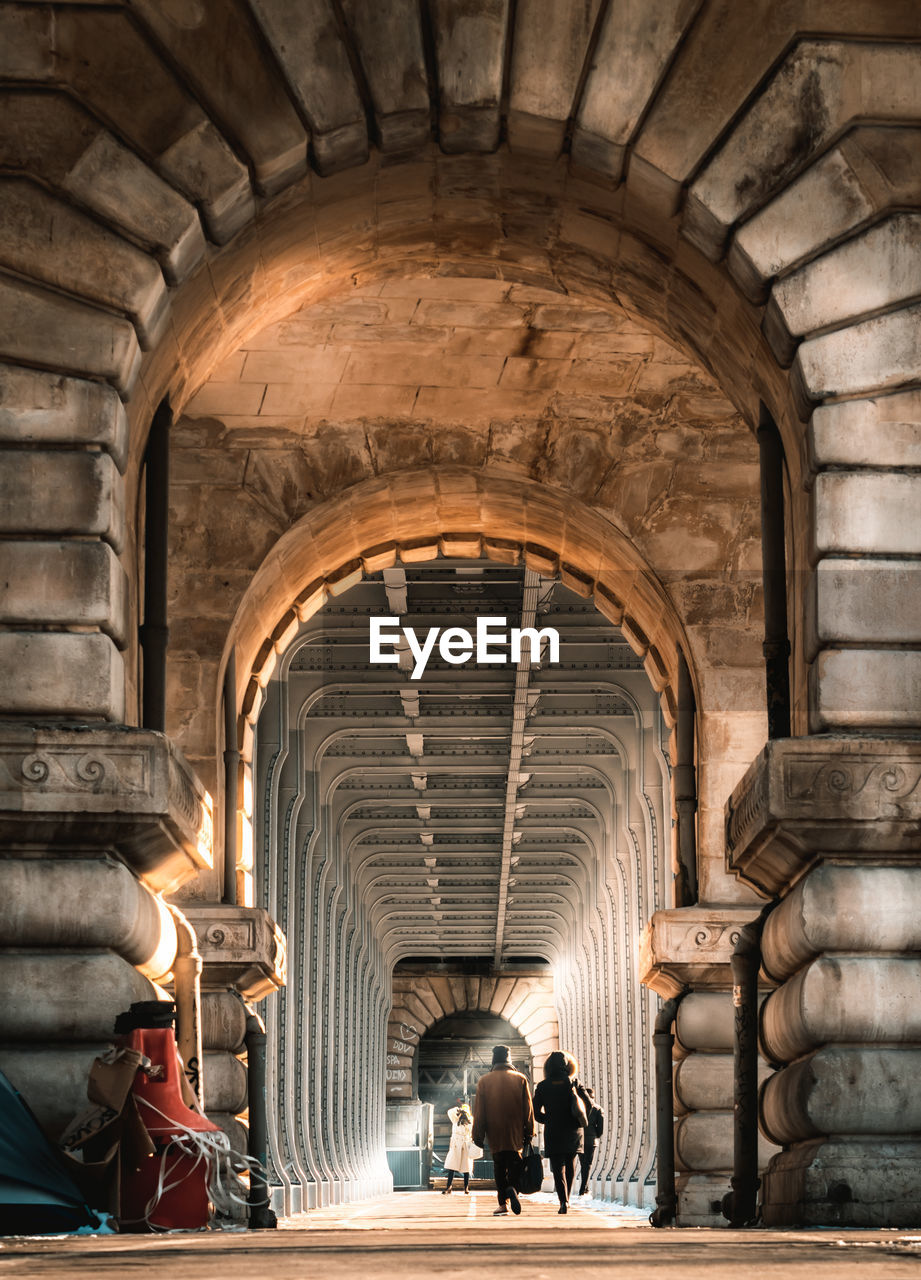 Rear view of people walking in corridor of historic building