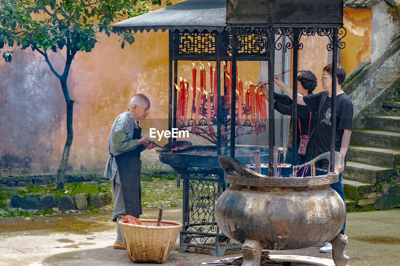 MAN STANDING IN TRADITIONAL CLOTHING AT OUTDOOR CAFE