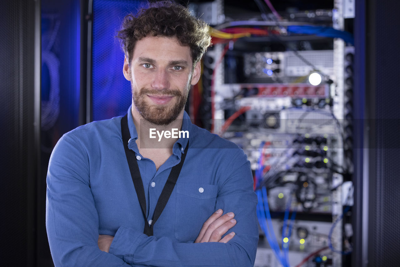 Male it specialist with arms crossed standing in data center