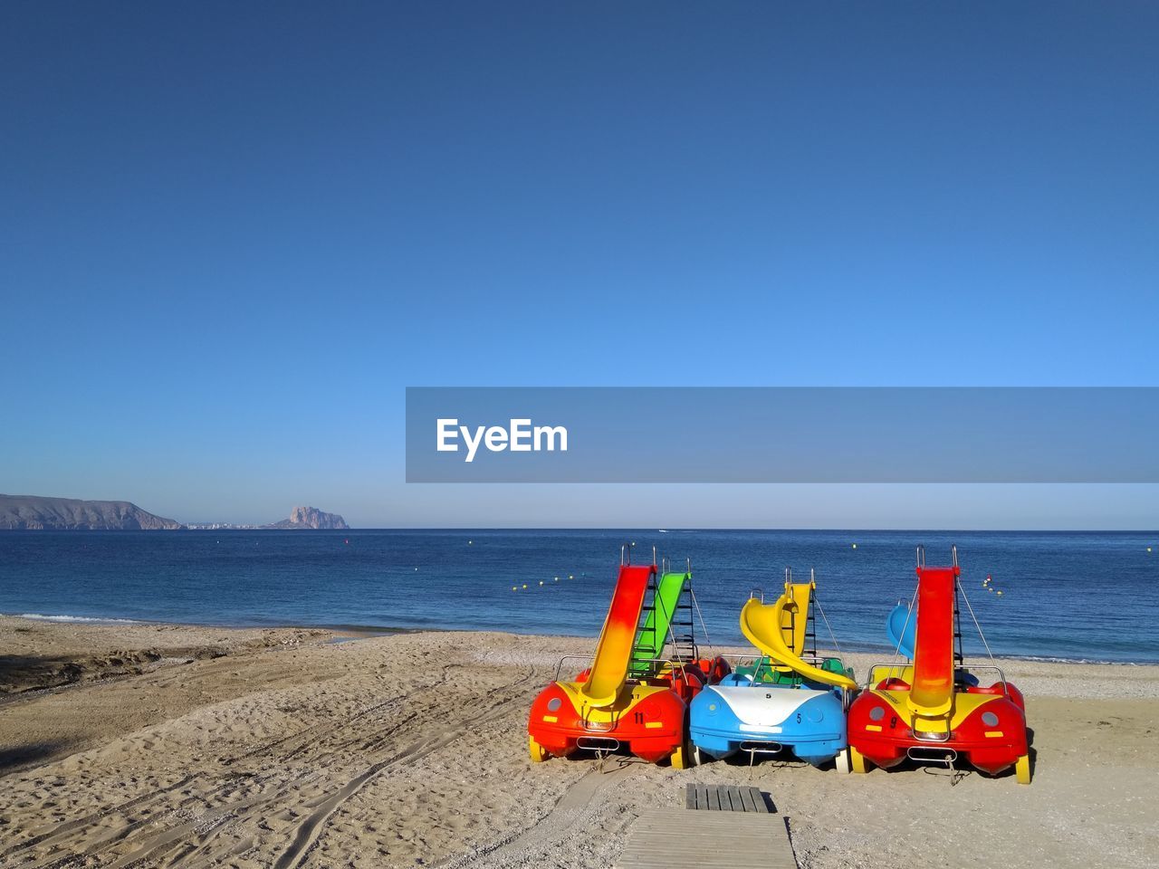 Catamaran on beach against clear blue sky