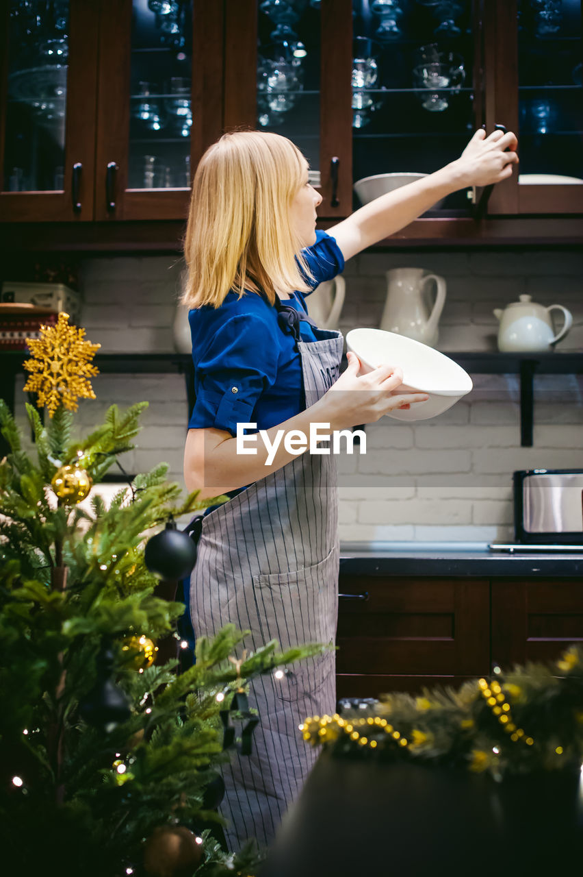 Woman taking bowl from kitchen cabinet