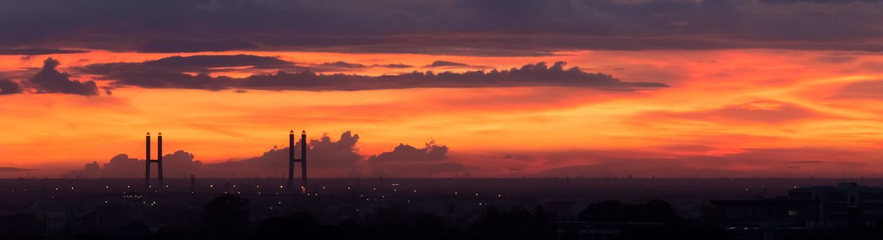 Illuminated land against cloudy sky during sunset