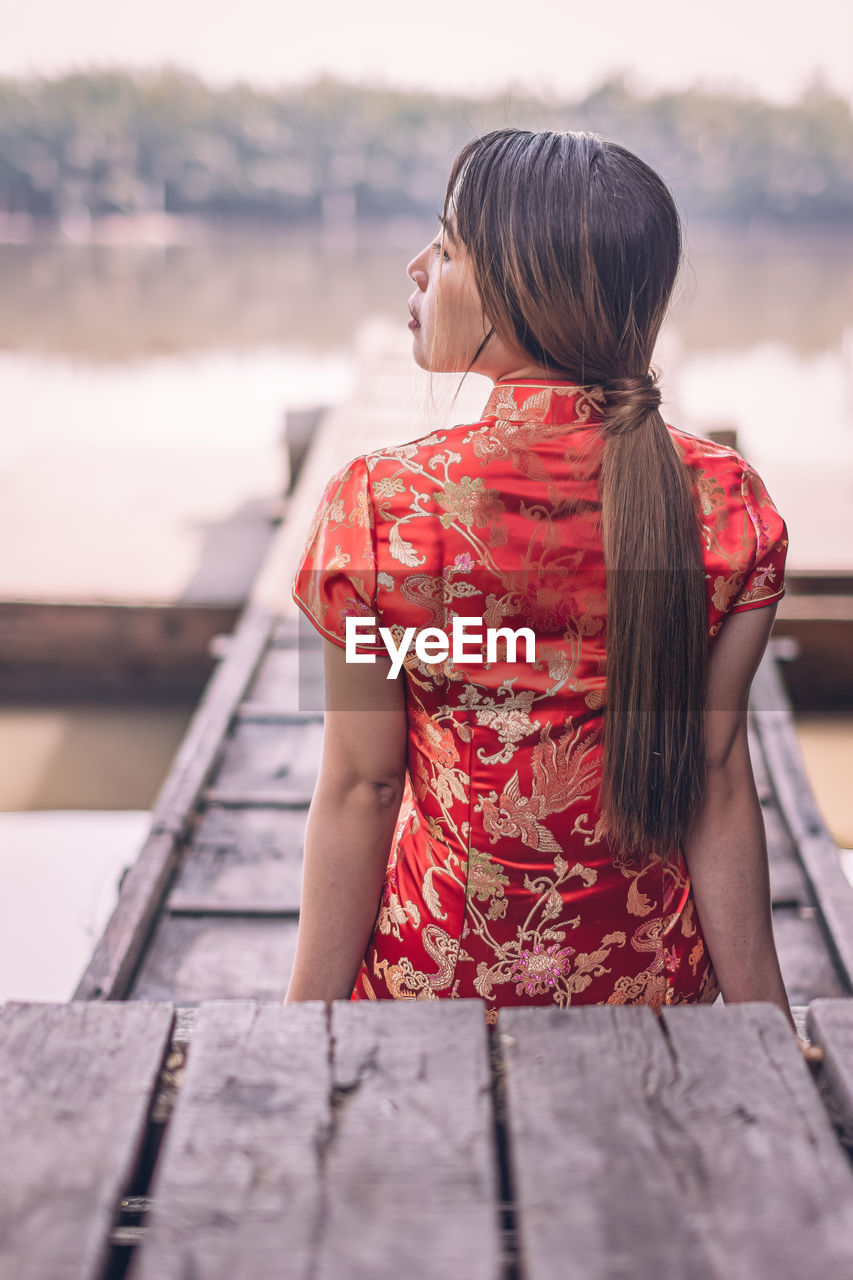 REAR VIEW OF WOMAN LOOKING AT PIER