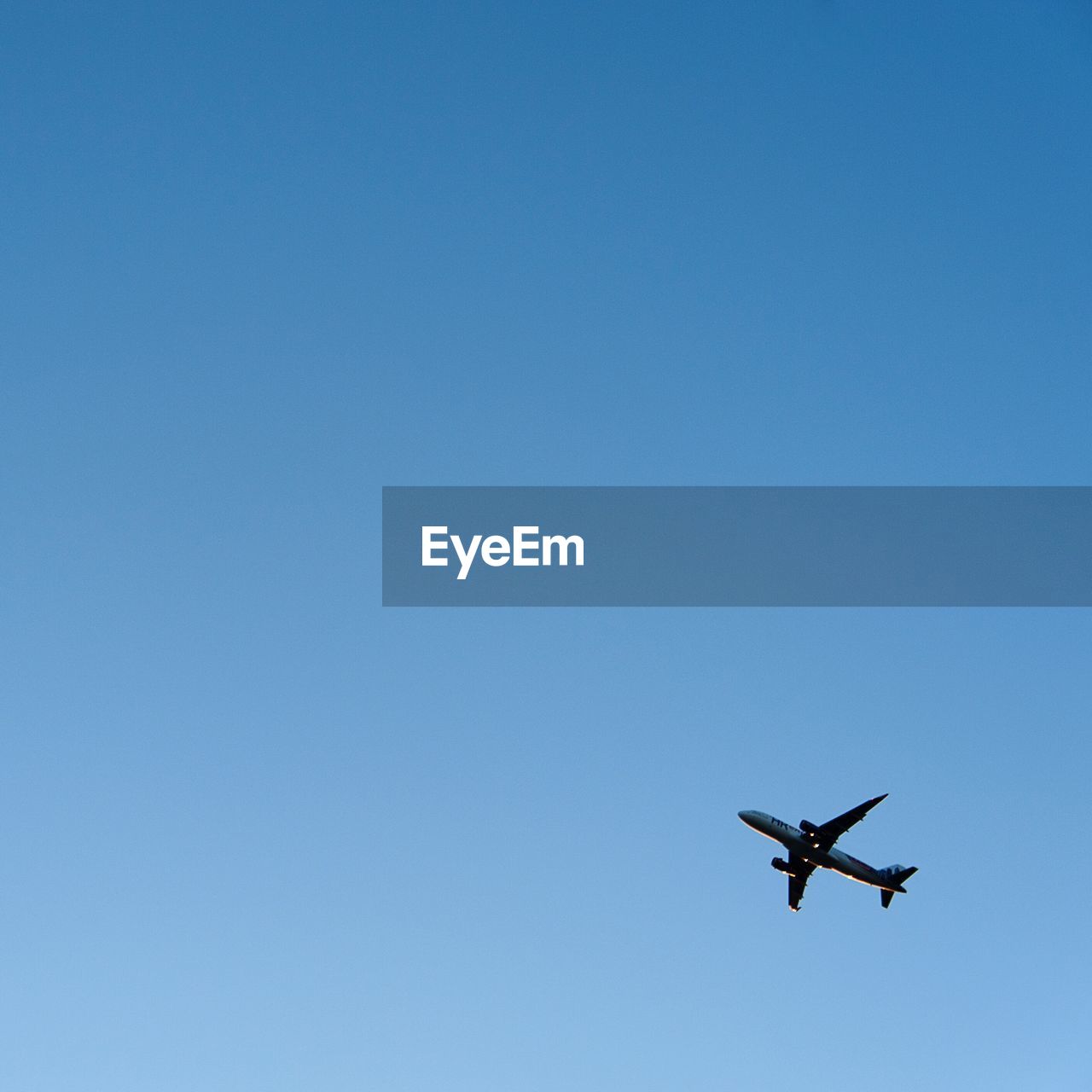 Low angle view of airplane flying in clear blue sky