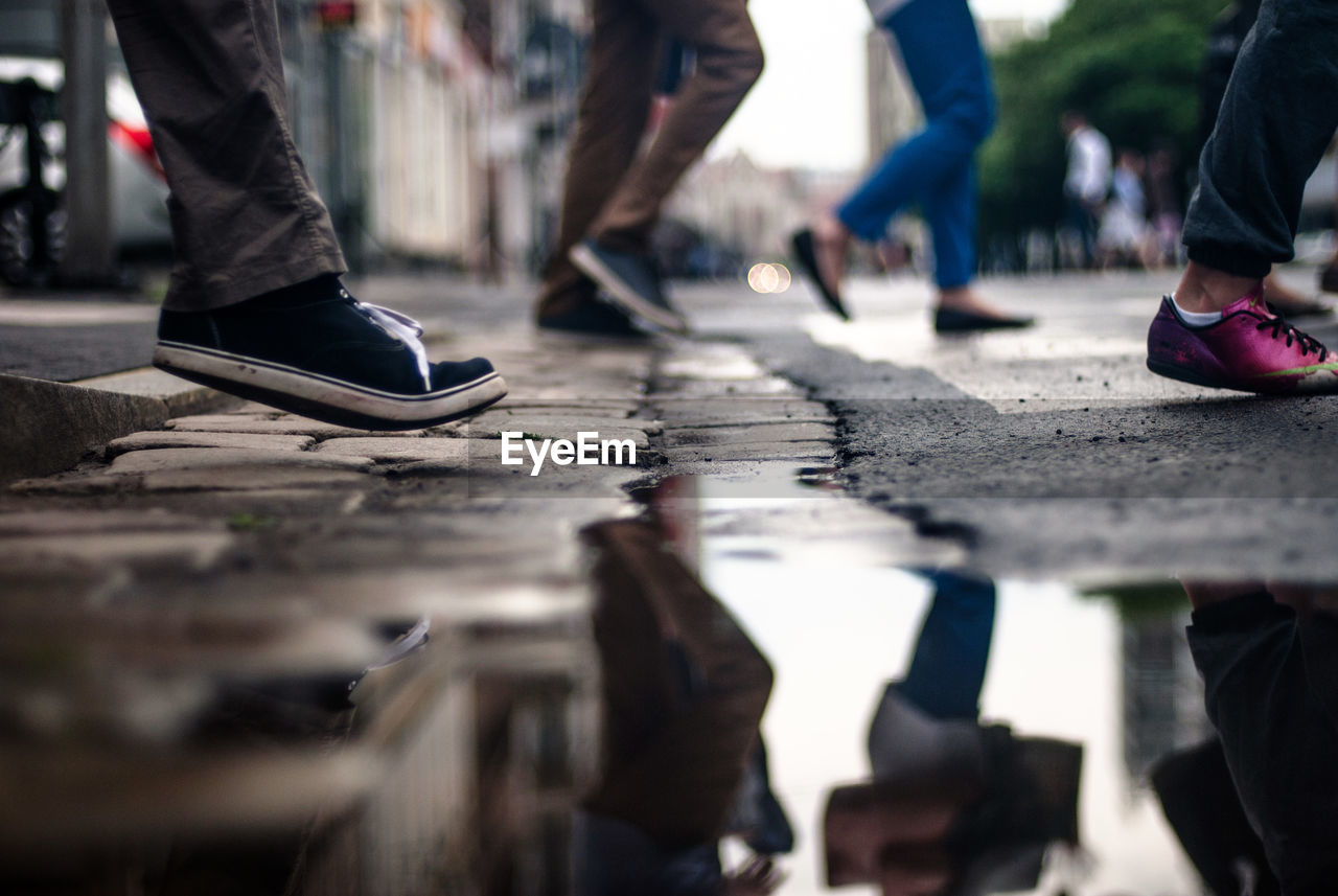 Low section of people walking by puddle