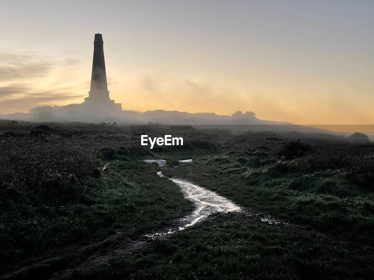 Carn brea monument, almost submerged in light fog, moment before sunset