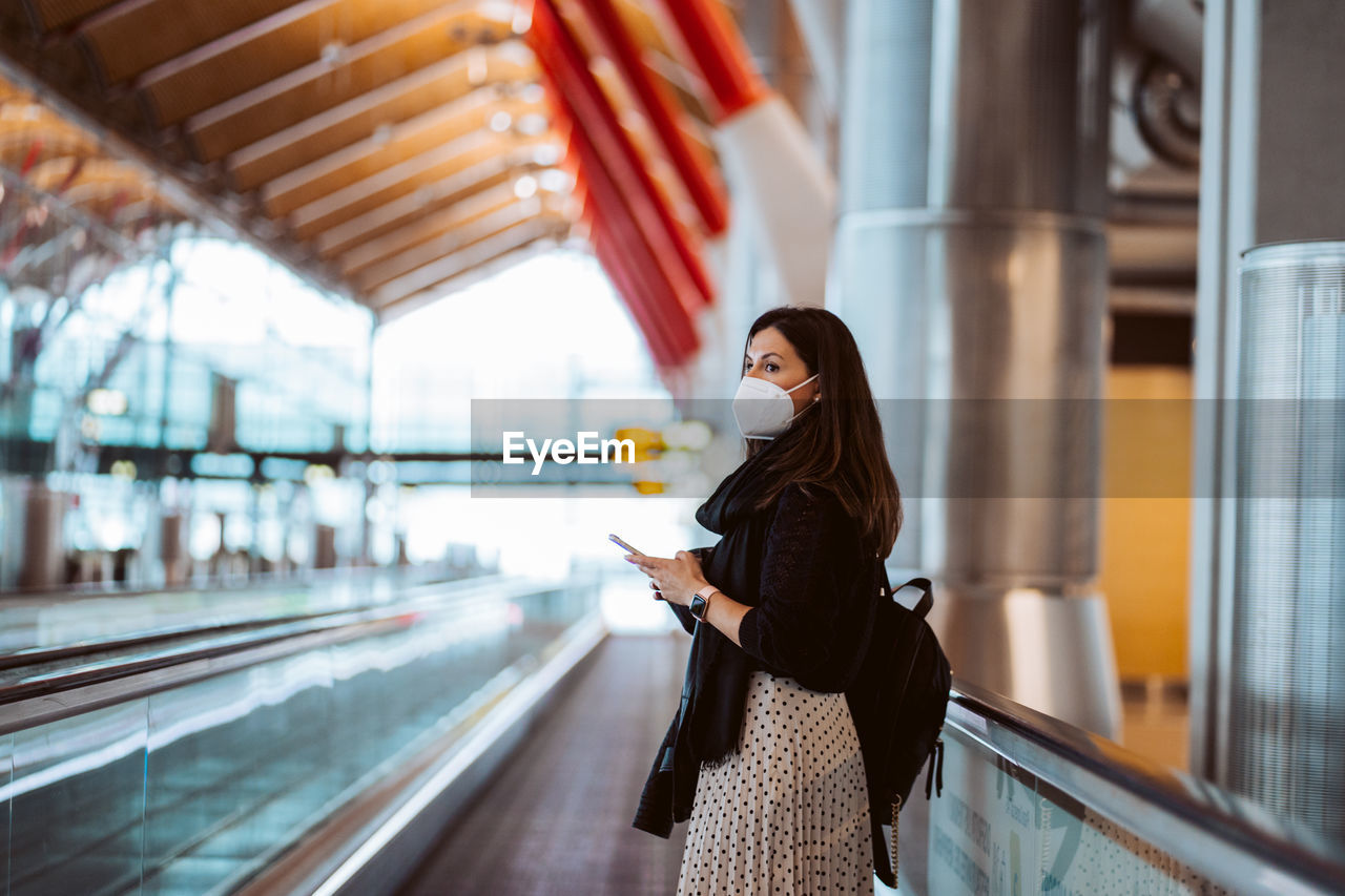 Side view of woman wearing mask standing at airport