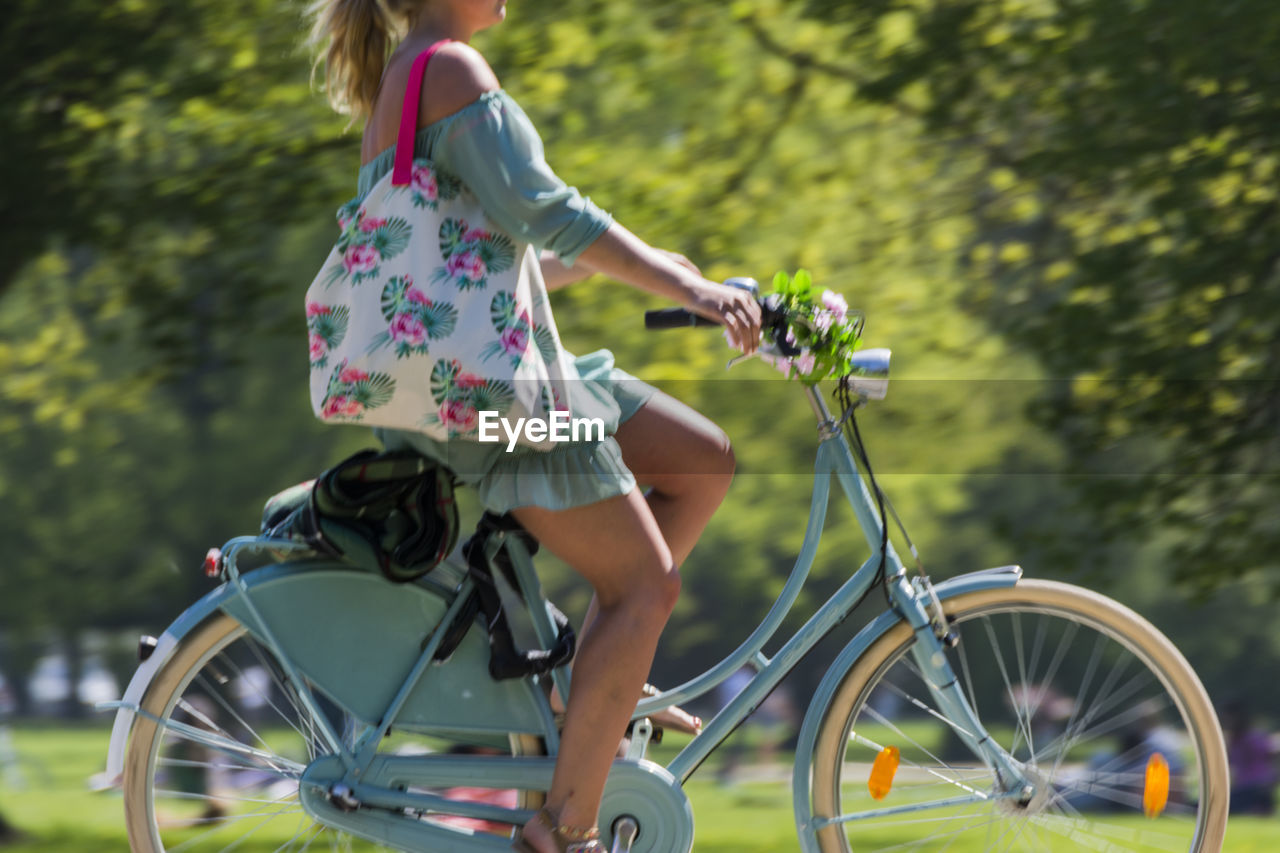 Low section of young woman riding bicycle in park