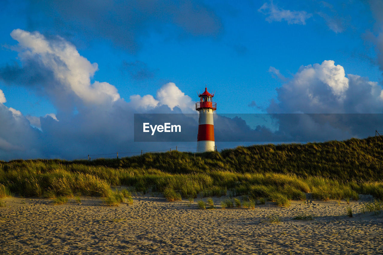 Red and white lighthouse by sea against sky on sylt