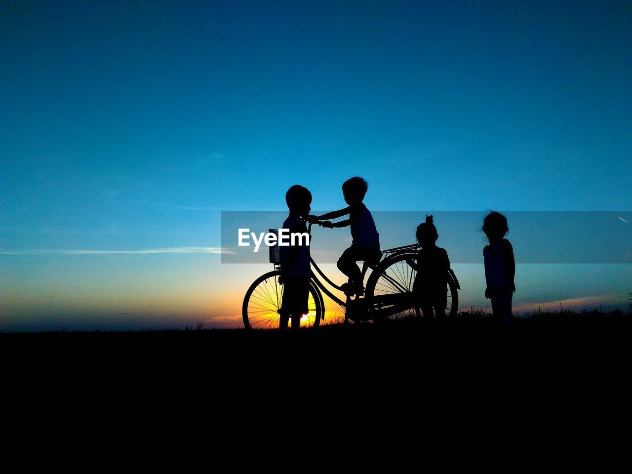 SILHOUETTE PEOPLE ON BICYCLE AGAINST CLEAR SKY