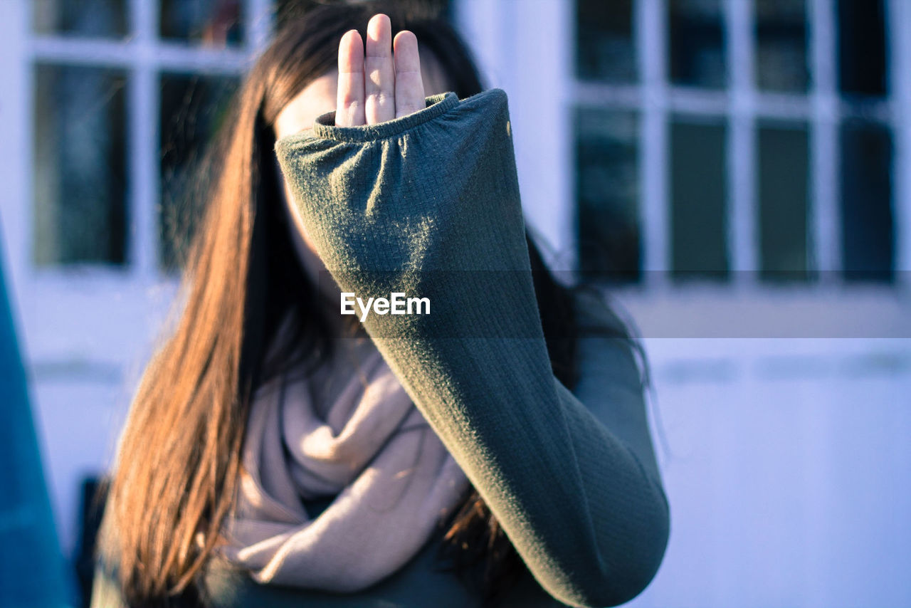 Close-up of woman covering face outdoors