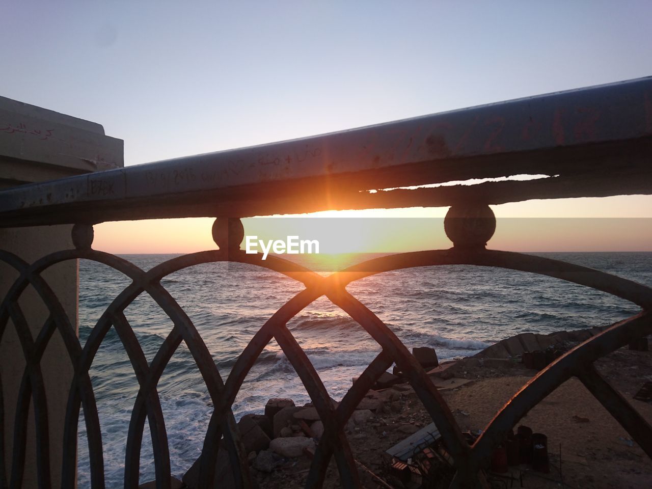 SILHOUETTE BRIDGE OVER SEA AGAINST SUNSET SKY