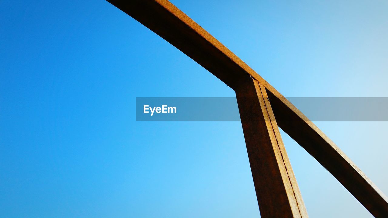 Low angle view of rusty metal structure against blue sky