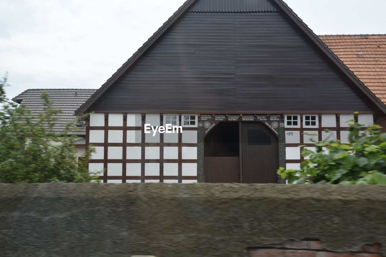 Exterior of house with plant and wall in foreground