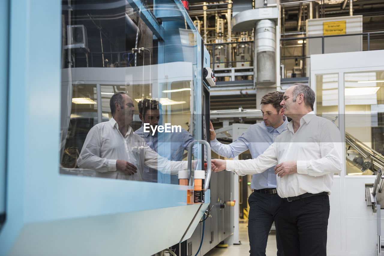 Two men looking at machine in factory shop floor