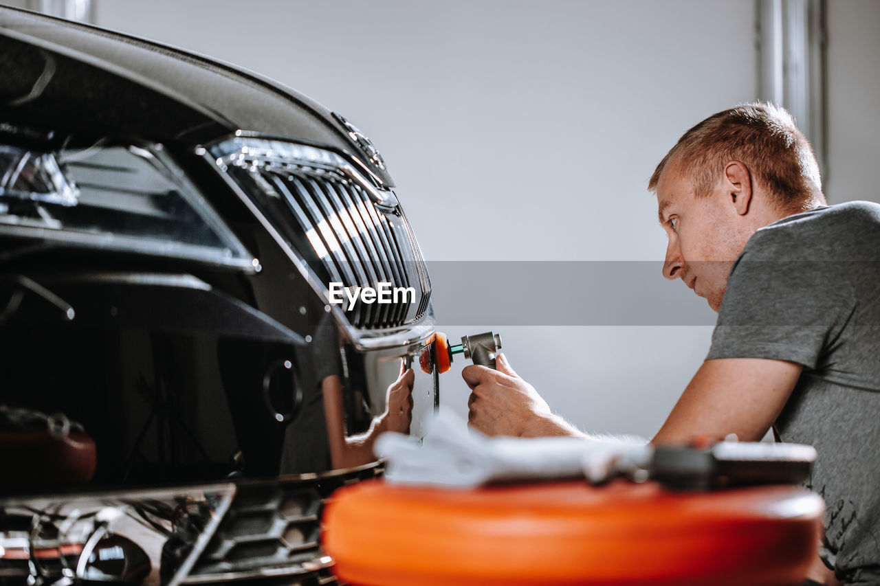 Mechanic polishing car at garage