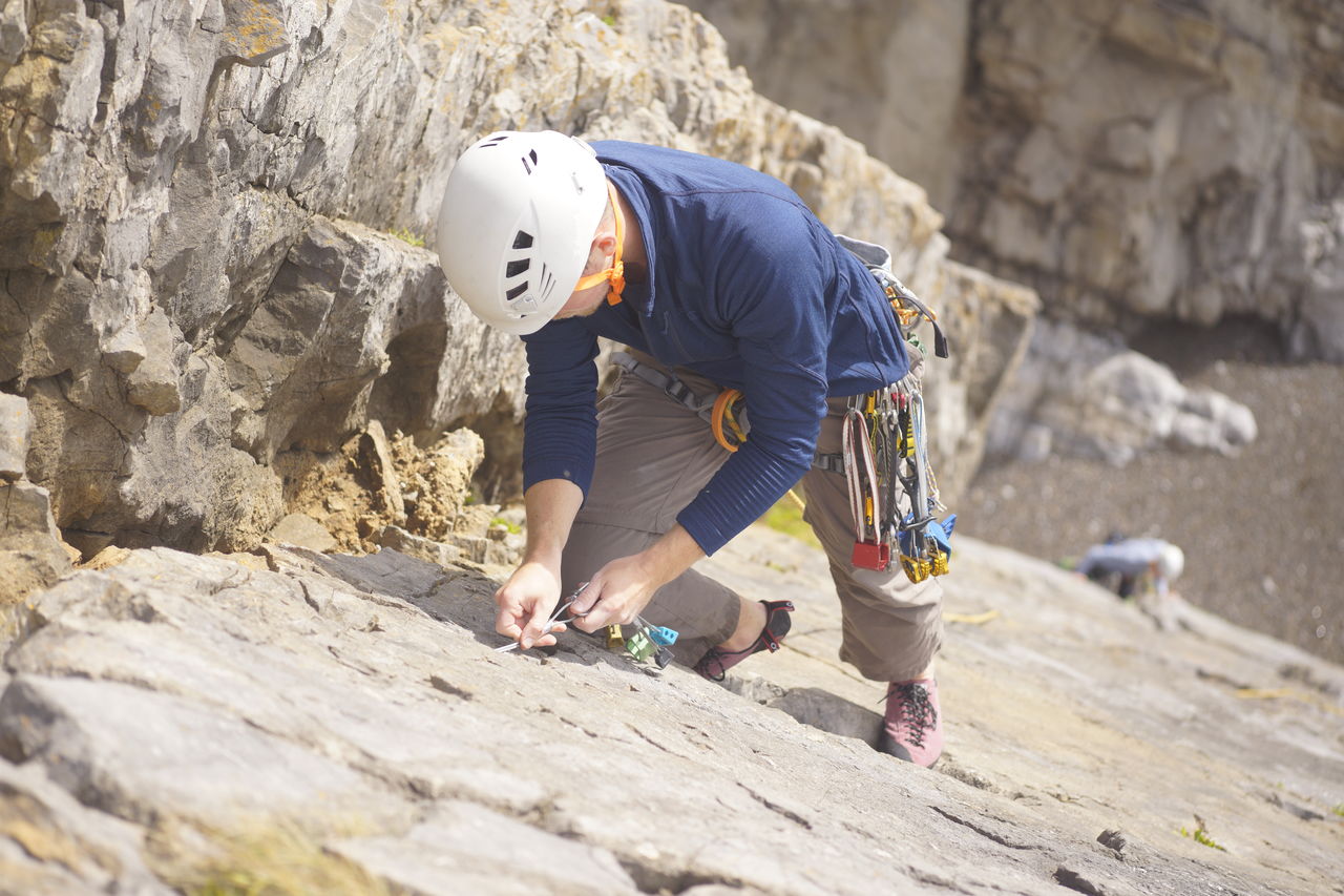 FULL LENGTH OF MAN CLIMBING ROCK