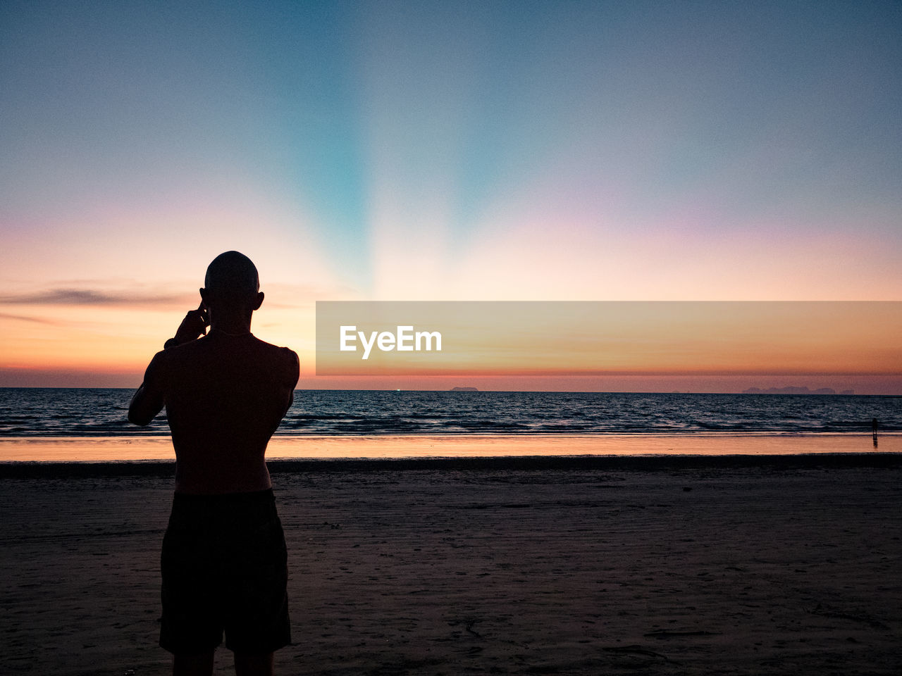 SILHOUETTE PERSON STANDING ON BEACH DURING SUNSET