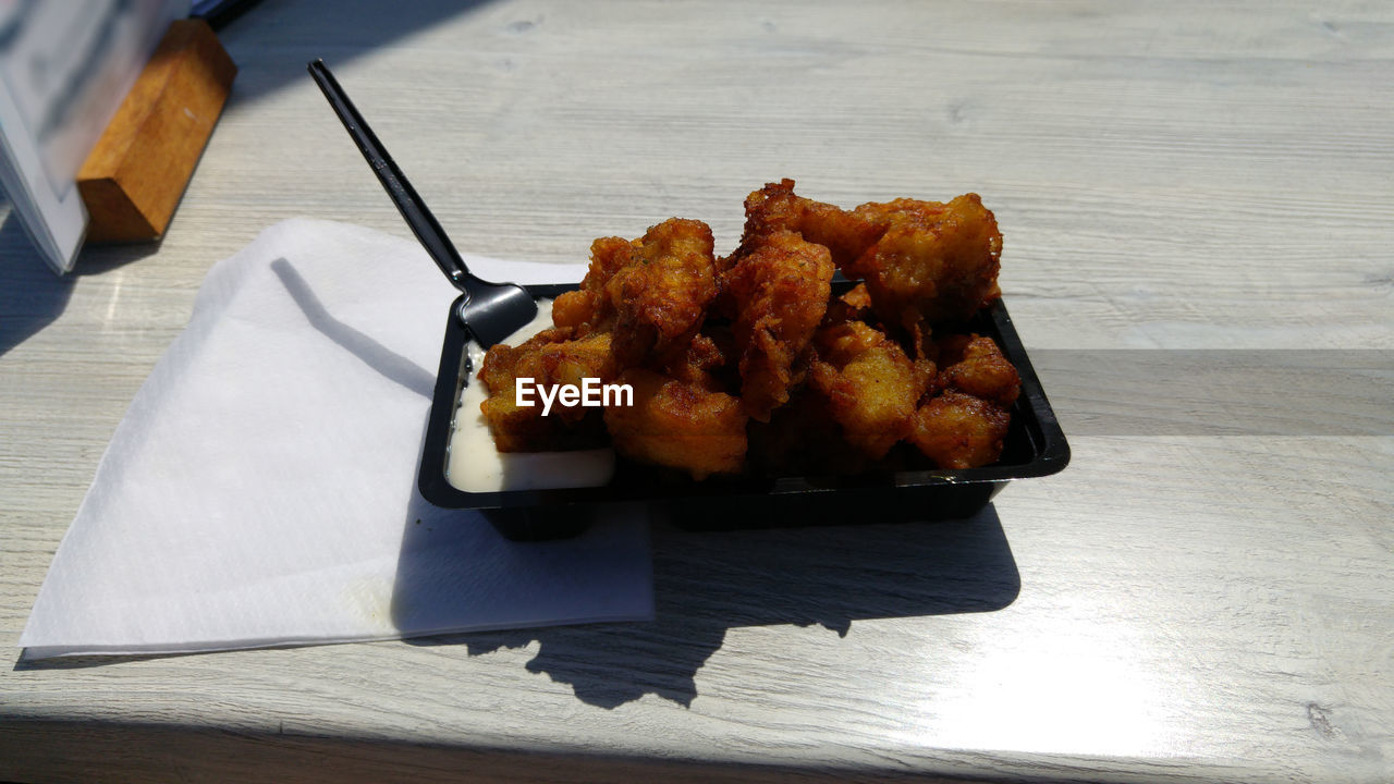 High angle view of fried meat in plate on table during sunny day