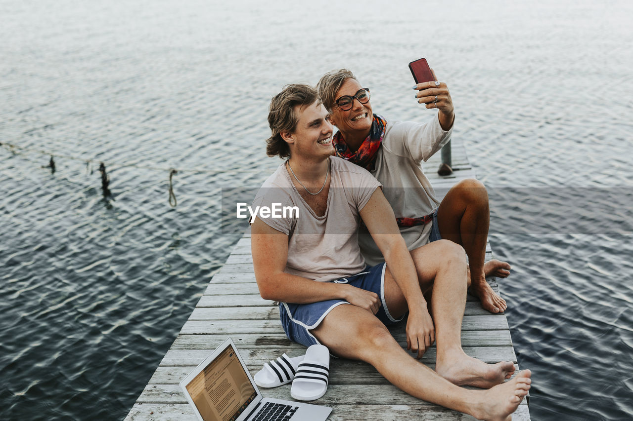 Mother with adult son on jetty taking selfie