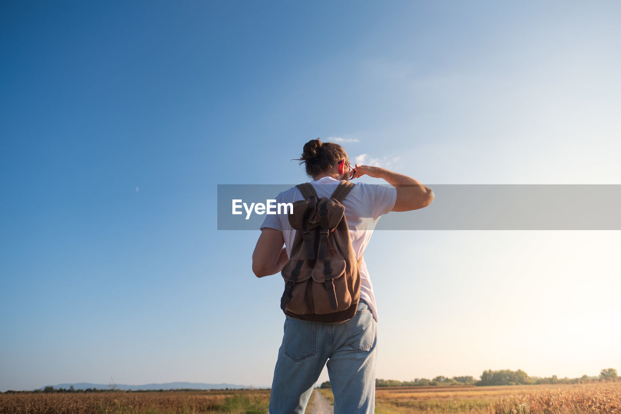 Rear view of man standing on land against sky