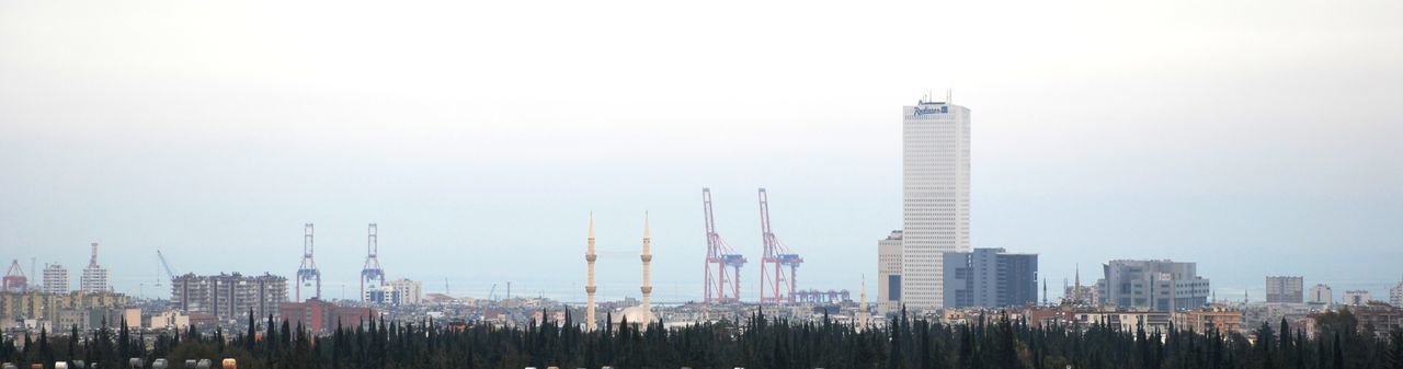 Panoramic view of buildings and cranes against sky